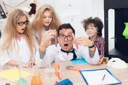 Children in white coats do chemical experiments during the lesson in the classroom.の写真素材