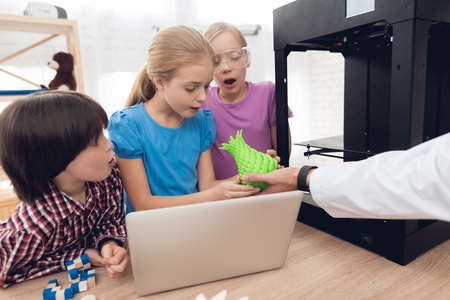 Children print different items on a 3d printer with a teacher.の写真素材