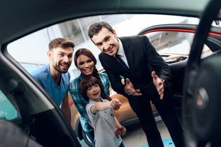 A young family came to the car showroom to choose a new car.の写真素材