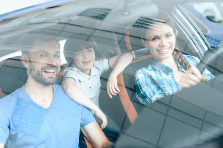 A woman is sitting at the wheel of a new car.