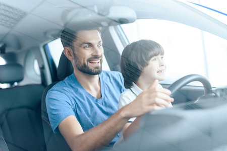 A man with a small son is sitting at the wheel of the car.の写真素材