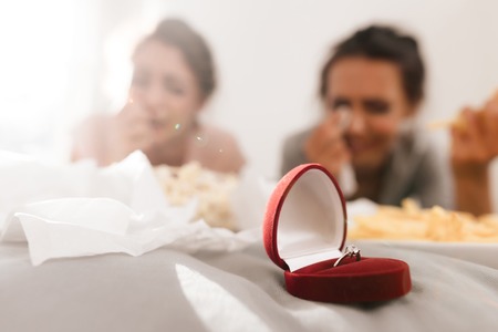 Girls are crying at the hen-party. They are lying on the bed and an engagement ring is near them.の写真素材