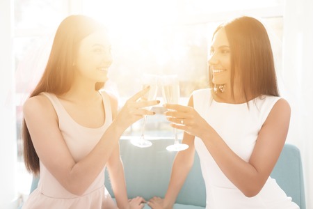 Pre-wedding care. Girls at a hen-party. They sit on the couch with a glass of champagne.の写真素材