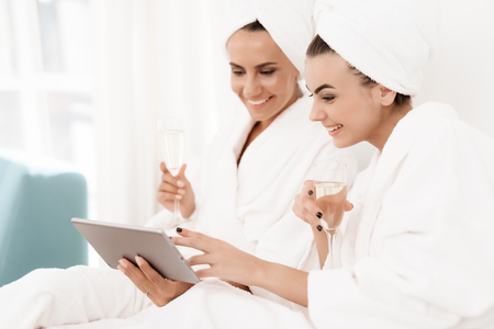 Girls have a great time at the hen-party. Brunettes in white bathrobes have fun in a bright room.の写真素材