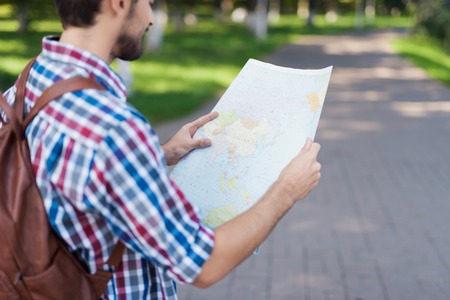 Close up. A man holds in his hands an expanded map of the world. He thinks where to go next.