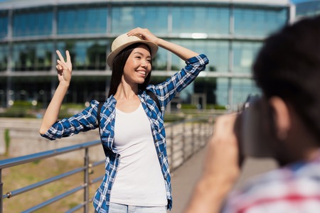A guy takes a picture of a beautiful girl against a beautiful modern building.の写真素材