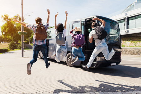 Four tourists jumped for posing in the photo. They are having fun. They stretched out their hands and smiled.の写真素材