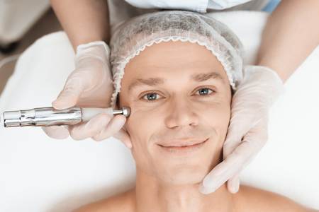 A man came to laser hair removal facial. Doctor leads him in the face with a modern laser epilator.の写真素材