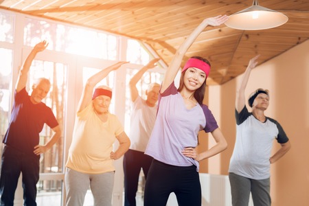 A group of elderly women and men doing therapeutic gymnastics in a nursing home.の写真素材