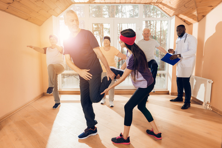 A group of elderly women and men doing therapeutic gymnastics in a nursing home.の写真素材