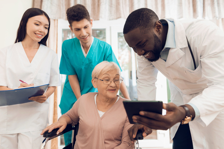 The doctor shows something on the tablet to an elderly patient in a nursing home.の写真素材