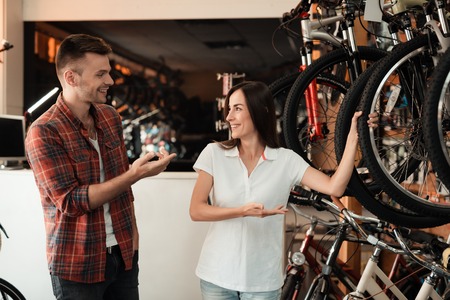 A girl consultant shows the buyer in a bicycle store.の写真素材