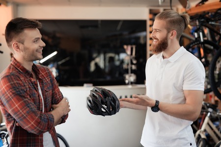 The man-seller shows the buyer a helmet for bike rides.の写真素材