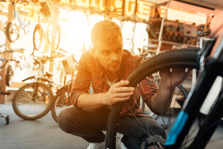 A young guy examines a wheel from a bicycle.の写真素材