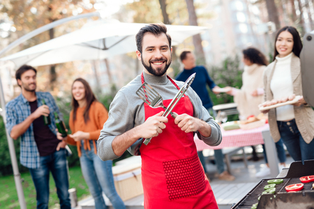 A man is posing on the camera while cooking food on the grill.の写真素材