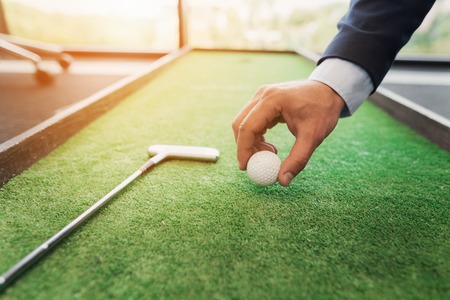 Close up. A man in a business suit plays golf in the officeの写真素材