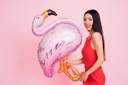 Girl with pink flamingo on pink background celebrating womens day March 8.の写真素材