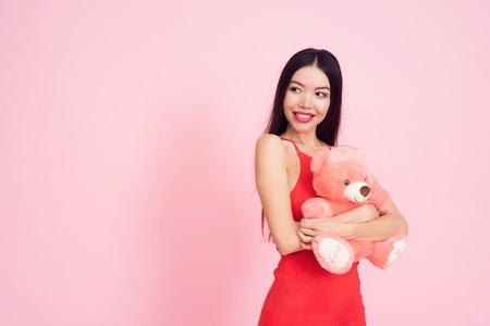 Girl with pink teddy bear on pink background celebrating womens day March 8.の写真素材