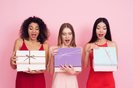 Three girls with presents on pink background celebrating womens day March 8.の写真素材