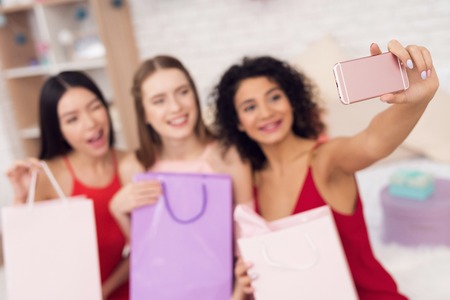 Three girls with shopping bags taking selfie. They are celebrating womens day March 8.の写真素材