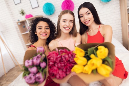 Three girls with flowers. They are celebrating womens day March 8.の写真素材