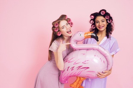 Two girls with hair curlers and flamingo baloon. They are celebrating womens day March 8.の写真素材