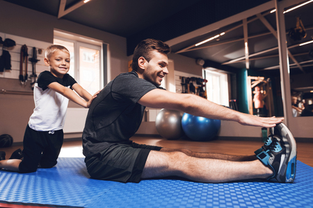 Father and son in the gym. Father and son spend time together and lead a healthy lifestyle. Man and boy are working out. Father and son are doing exercise.の写真素材