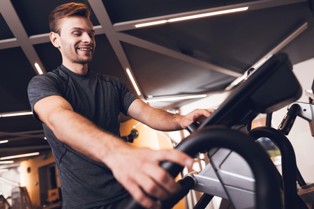 A man is doing sports in the gym. He leads a healthy lifestyle. A man is engaged in an elliptical trainer.の写真素材