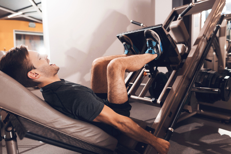 A man is doing sports in the gym. He leads a healthy lifestyle. Man is engaged on the simulator in the support lying down.の写真素材