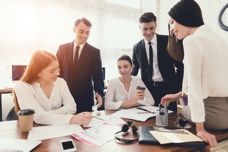 A group of young people holds brainstorming in the office. They work in a call center and discuss...