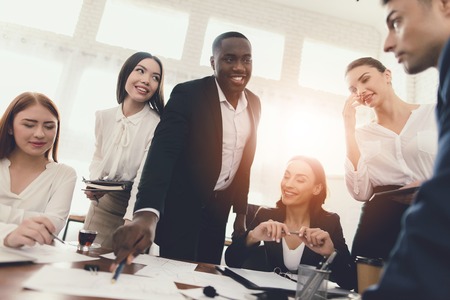 A group of young people holds brainstorming in the office. They work in a call center and discuss...