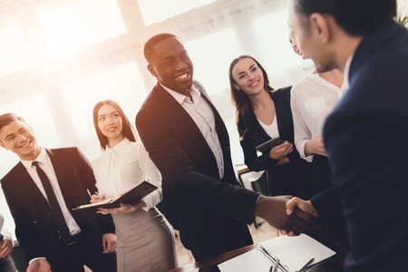 A group of young people holds brainstorming in the office. They work in a call center and discuss...