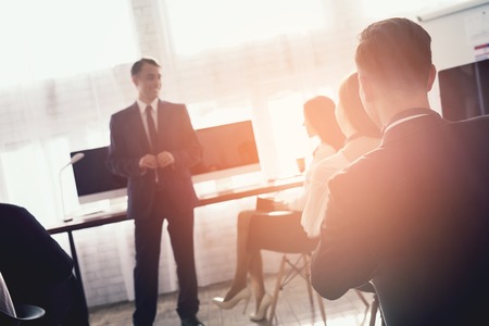 A man of Arabian appearance is giving a lecture for office workers. They have a conference. A man motivates his colleagues.の写真素材