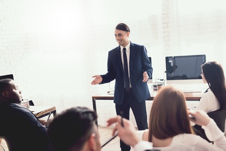 A man of Arabian appearance is giving a lecture for office workers. They have a conference. A man motivates his colleagues.の写真素材