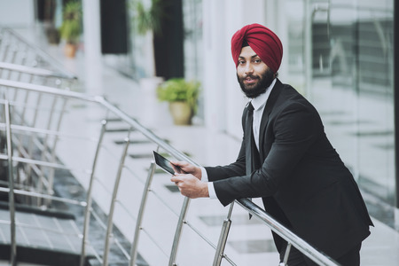 Young indian businessman in modern office with tablet.の写真素材