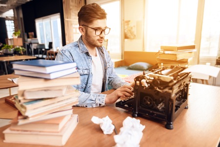 Freelancer man in jeans shirt typing at old typewritter sitting at desk.の写真素材