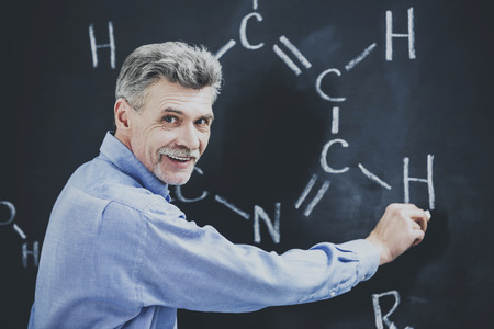 Professor of chemistry writes on the blackboard formula in University.の写真素材
