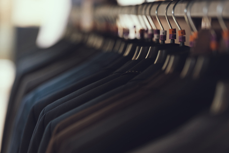 Close up. Business mens suits hang on hangers in boutique of business clothes. Big choice of suit. Wardrobe. Dressing room.の写真素材