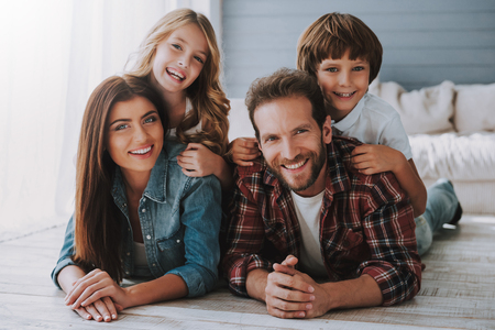 Large happy family lies together on floor. Parents spend fun with children.の写真素材
