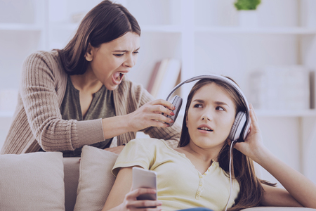 Teen closed ears with headphone while mom yells at her.Problems between generations concept.の写真素材