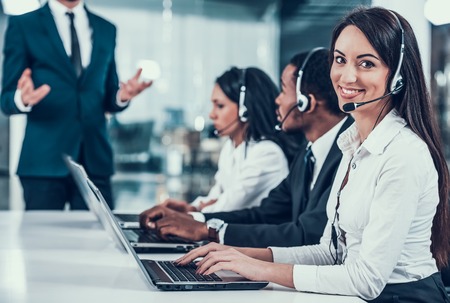 Multicultural young happy employees in call center sitting at computers and working. Teamwork. Employees in headset.の写真素材