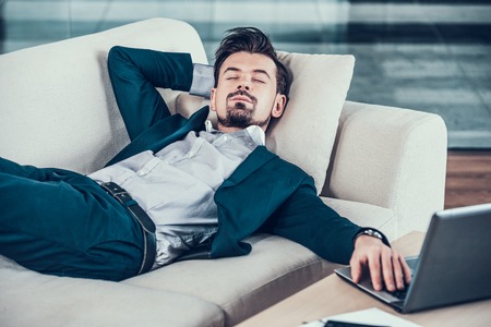 Tired bearded businessman asleep on sofa in office.Business people.Rest in office.の写真素材