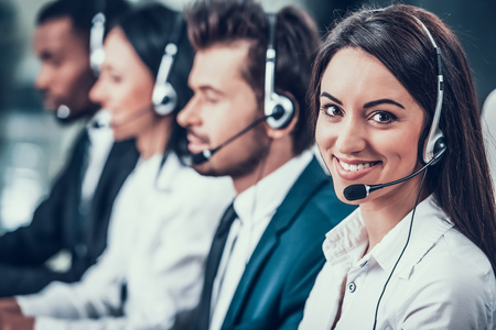 Multicultural young happy employees in call center sitting at computers and working. Teamwork. Employees in headset.の写真素材