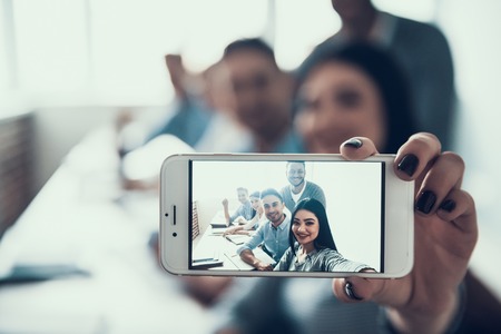 Young Student Taking Selfie in Classroom. Taking Photo on Phone. Friends in College. Happy Attractive People. Multiethnic Friendship. Communication with Friends Concept. Selfie with Friends.の写真素材