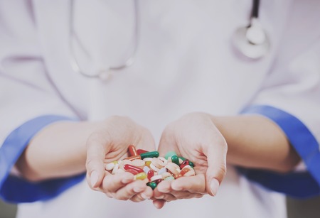 Close up. Focus on Hands of Doctor Holding Pills. Medical Staff concept. Work in Hospital. Concept of Health Care. Medical Consultant. Clinical Concept. Standing in Hospital. Woman in Uniform.の写真素材