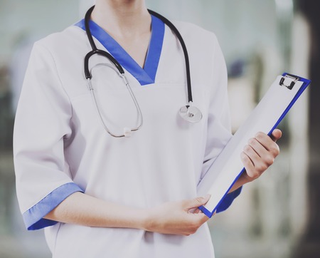 Close up. Young Female Doctor with Stethoscope. Concept of Health Care. Medical Consultant in Clinic. Holding Tablet in Hand. Clinical Concept. Standing in Hospital. Woman in Uniform.の写真素材