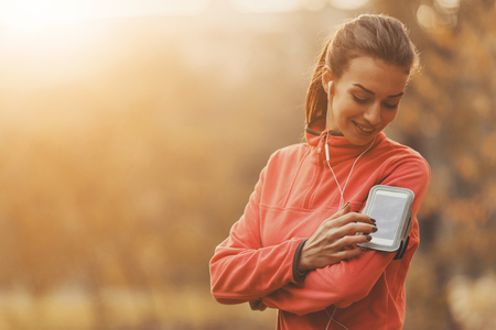 Girl Choose Music for Running. In Autumn Park. Young Beautiful Woman Doing Sports. Listening Music Composition. Fmale With Headphones. Fitness Concept. Running in Park. Sport Lifestyle.の写真素材