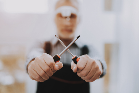 Standing Old Worker with Screwdrivers in Hands. Worker with Tools. Modern Workshop Concept. Manufacturing Instrument. Modern Tools Concepts. Man with Industry Device. Standing Man.の写真素材