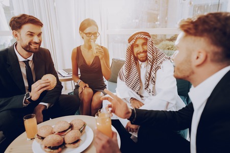 Arabian Businessman Is Having A Dinner With Partners. Money Investment. Talking With Managers. Partnership Agreement. Disdash And Keffiyeh Wearing. Eating A Burgers. Business Discussion.の写真素材