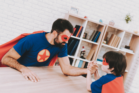Father And Son. Red And Blue Superhero Suits. Arm Wresling Competition. Masks And Raincoats. Bright Room. Young Happy Family Holiday Concept. Resting Together. Strong And Powerful.の写真素材